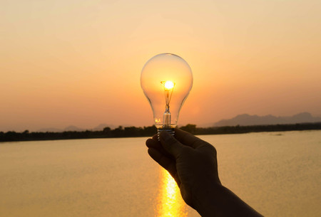 concept hand hold lightbulb and sunset background nature ideaの写真素材