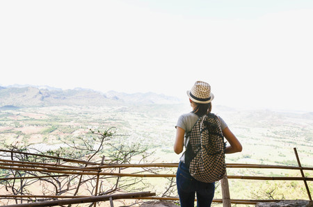 Woman traveler looks at the edge of the cliff on the mountains hiの写真素材