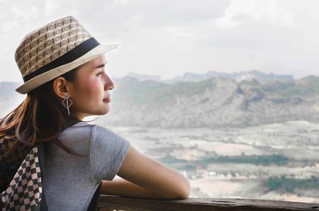 Woman traveler looks at the edge of the cliff on the mountains hiの写真素材