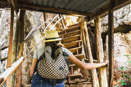 Woman traveler walking up level of staircase the cliff on the mountains hi