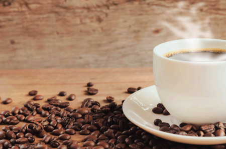 cup of coffee with beans on table background