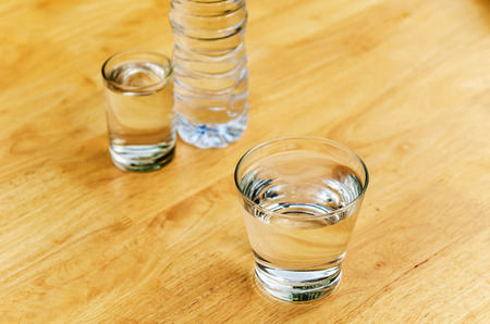 Drinking water in a glass with a bottle on the table.