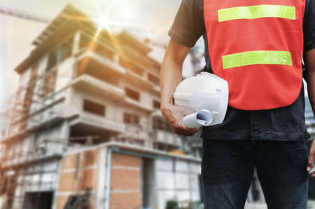construction worker checking building with holding helmet and crane  background