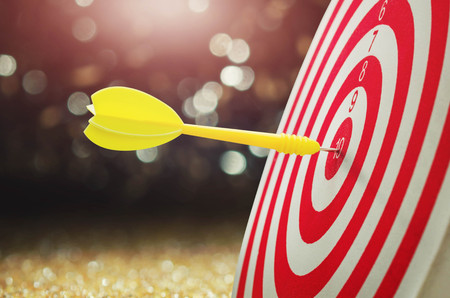 yellow arrow with over blurred background and target of dartboard or metaphor to target business conceptの写真素材