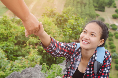 hand hold helping young woman traveler on top mountainの写真素材