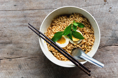 bowl of noodles with vegetables Basil and egg on old woodenの写真素材