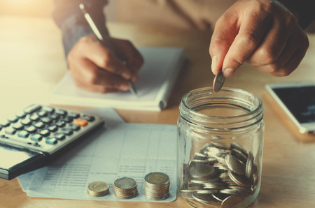 business accountin with saving money with hand putting coins in jug glass concept financialの写真素材