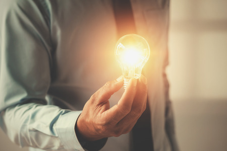 hand businessman holding light bulb, innovation and inspiration conceptの写真素材
