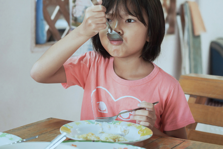 asian children eating breakfast in kitchenの写真素材