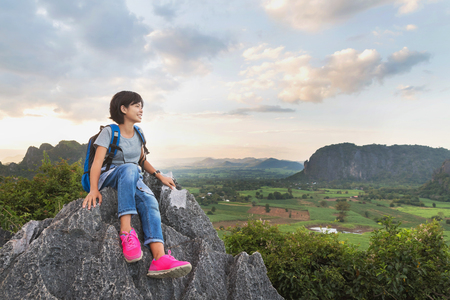 asian young woman with backpack sitting on rock of mountain, travel lifestyle conceptの写真素材