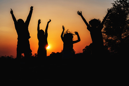 group people jumping silhouette with sunsetの写真素材