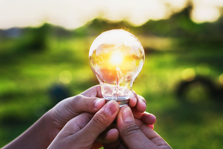 group hand holding lightbulb with sunset. concept idea solar energy