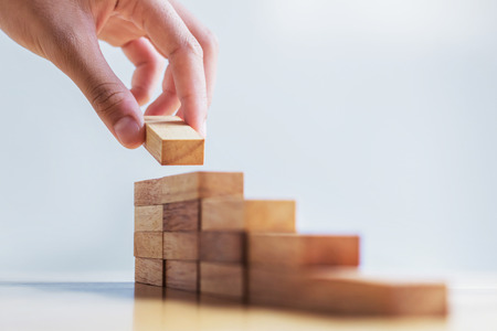 hand stack woods block step on table. business development concept