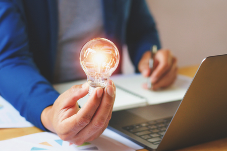 businessman holding lightbulb in office. creative idea for saving energy. concept financeの写真素材