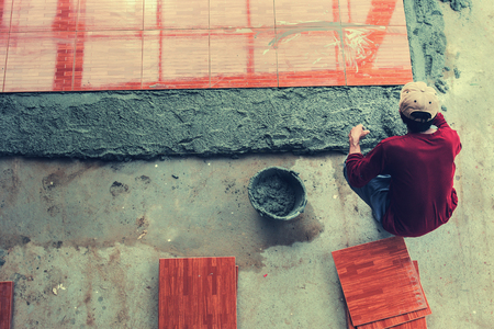 Top view of construction worker laying tiles on floorの写真素材