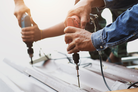 Carpenters using mechanical screwdriver on the roofの写真素材