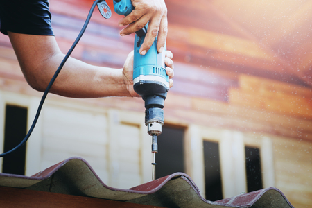 Carpenter using mechanical screwdriver on the roofの写真素材
