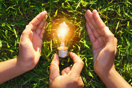 hand holding protection lightbulb on grass. concept saving energyの写真素材