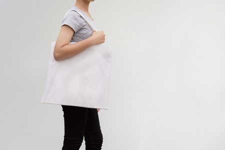young woman holding cotton bag on wall background. eco conceptの写真素材
