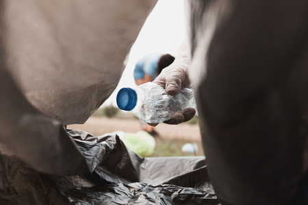 hand holding bottle garbage putting in to black bag for recycle cleaning