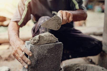 hand of worker plastering cement on brick wall at construction siteの写真素材