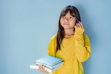 girl student  holding pile of books isolate on blue background