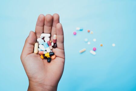 medicine and pills in hand on blue background. health care concept