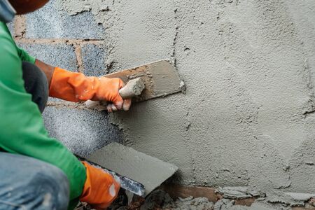 worker plastering cement on wall for building houseの写真素材