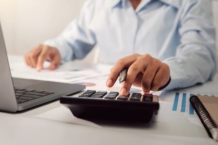 businesswoman working on desk using calculator analyzing finance accounting in office 