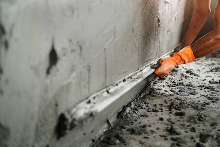 closeup hand of worker plastering cement at wall for building houseの写真素材