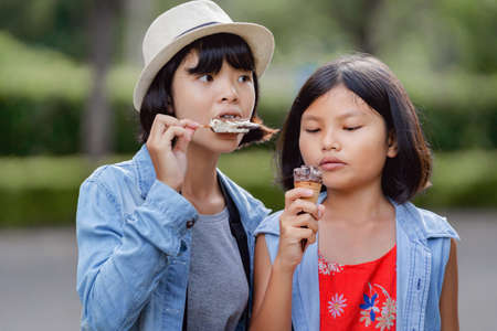two girl eating ice cream on street during walking travel at parkの写真素材