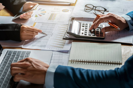 businessman use calculator and computer for  meeting with team accountant on desk in office. finance and accounting conceptの写真素材