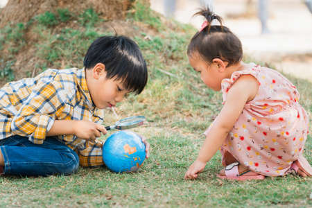 children boy and girl looking at globe for learning world mapの写真素材