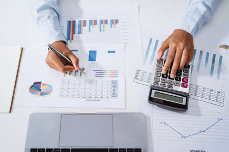 Woman accountant use calculator and computer with holding pen on desk in office. finance and...