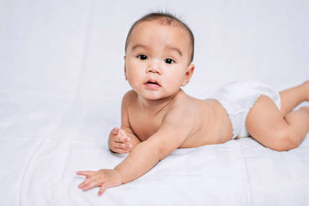 asian cute baby boy on white bed in roomの写真素材