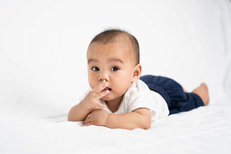 asian cute baby boy on white bed in roomの写真素材
