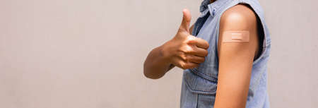 Portrait of a young female  showing thumbs up after getting a vaccine. standing on white backgroundの写真素材