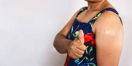 Portrait of a senior female  showing thumbs up after getting a vaccine. standing on white backgroundの写真素材