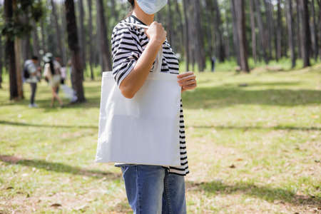 hipster woman holding white cotton bag at parkの写真素材