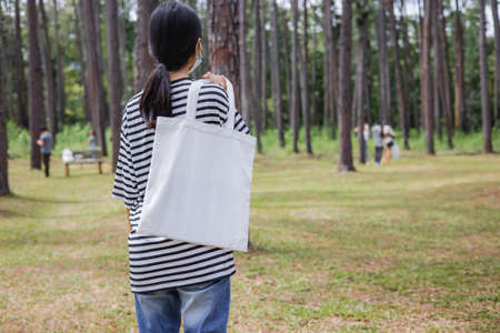 hipster woman holding white cotton bag at parkの写真素材