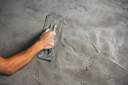 closeup hand of worker plastering cement at wall for building houseの写真素材