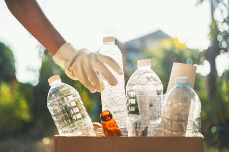 hand holding garbage bottle plastic putting into recycle bag for cleaningの写真素材