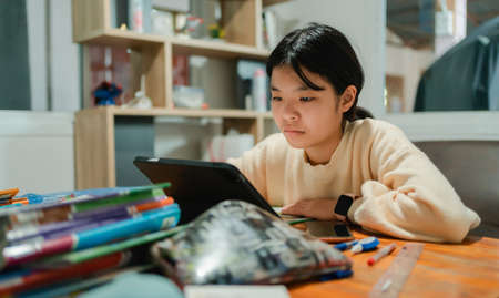 asian girl student learning online in computer tablet. indoors on desk at homeの写真素材