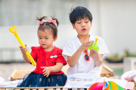 asian little girl and boy playing with toys by at homeの写真素材