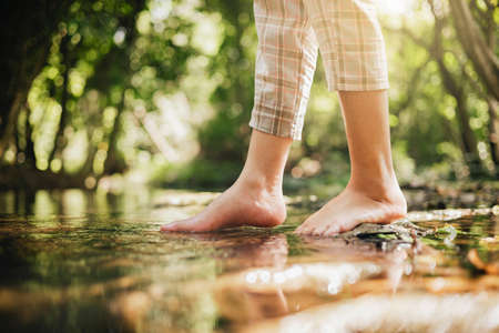 woman wading barefoot in stream in nature forestの写真素材