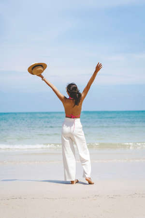 Female traveler happily raising their hands on the beach