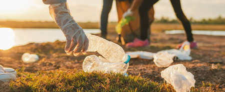 woman hand picking up garbage plastic bottle for cleaning at parkの写真素材