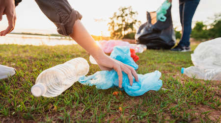 woman hand picking up garbage plastic bottle for cleaning at parkの写真素材