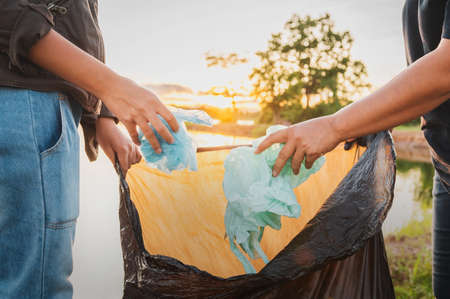 woman hand picking up garbage plastic bag for cleaning at parkの写真素材