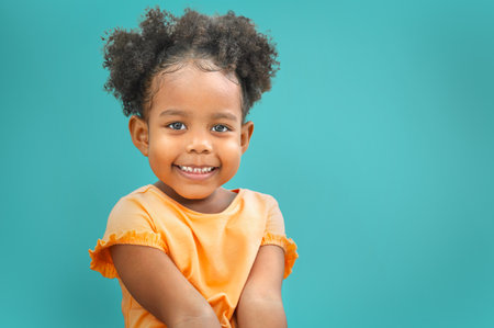 Sweet little girl outdoors with curly hair smiling on blue backgroundの写真素材